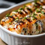 A close-up shot of a sushi bake recipe in a white dish, topped with a golden-brown, creamy layer and surrounded by crispy nori sheets, captured with natural light.