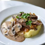 Potato Beef Stroganoff served in a white dish with creamy sauce, tender beef, potatoes, and mushrooms