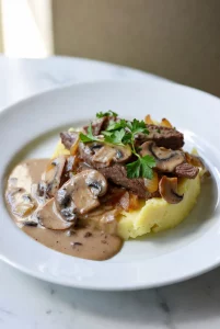Potato Beef Stroganoff served in a white dish with creamy sauce, tender beef, potatoes, and mushrooms