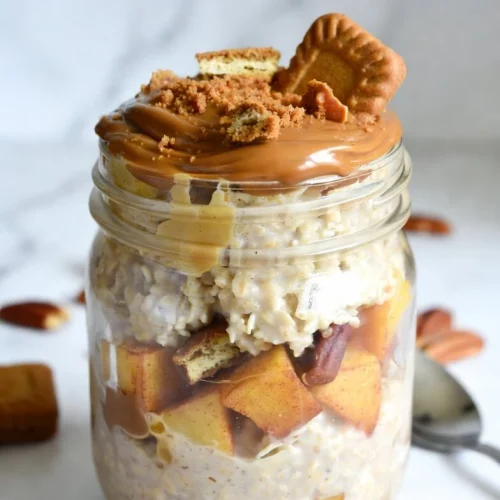 Biscoff overnight oats in a mason jar topped with melted cookie butter drizzle and crumbled Lotus Biscoff cookies