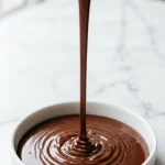 Chocolate ganache being poured into a white dish
