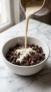 Hot cream poured over chopped chocolate in a bowl