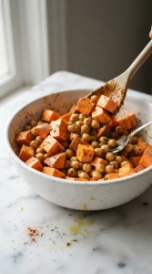 Sweet potato and chickpeas being seasoned for buddha bowl