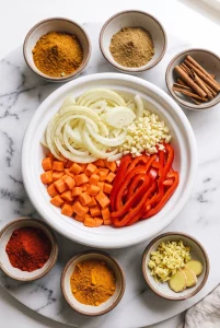 Sliced onion, garlic, carrots, and bell pepper for chicken tagine