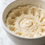 Side-angle close-up of creamed butter and sugar showing soft, airy peaks